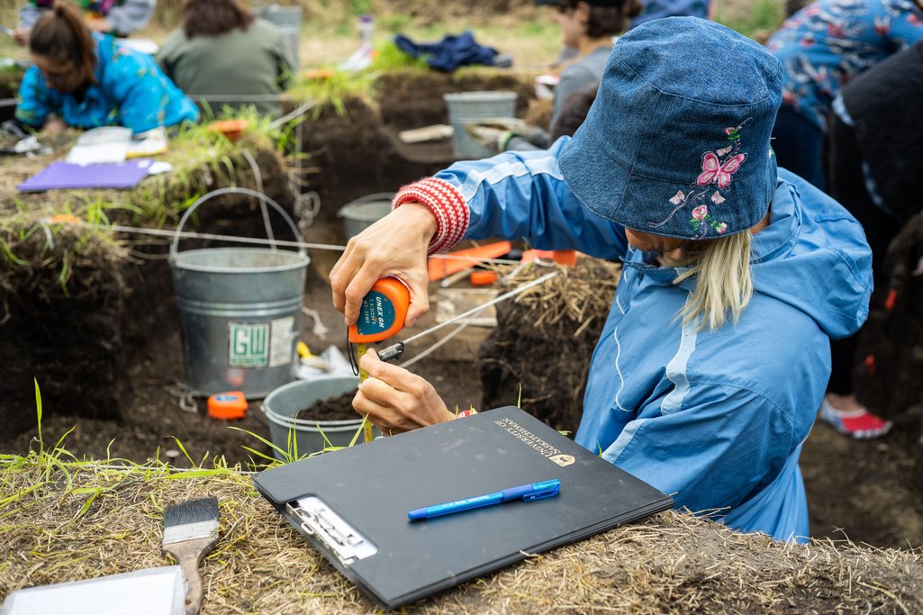 Person using measuring tape at archeological dig site at Wanuskewin Heritage Park