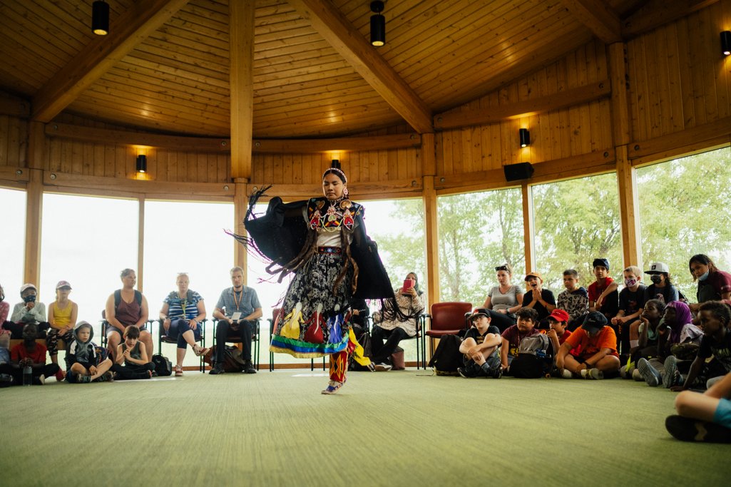 Saskatchewan Indeigenous dancer dancing in the middle of a circle inside Wanuskewin Heritage Park building
