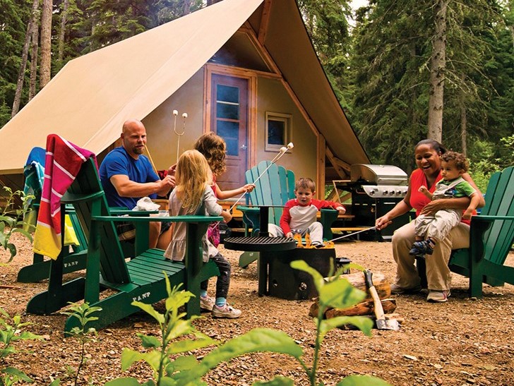 a group of people sitting around a campfire outside of a tent