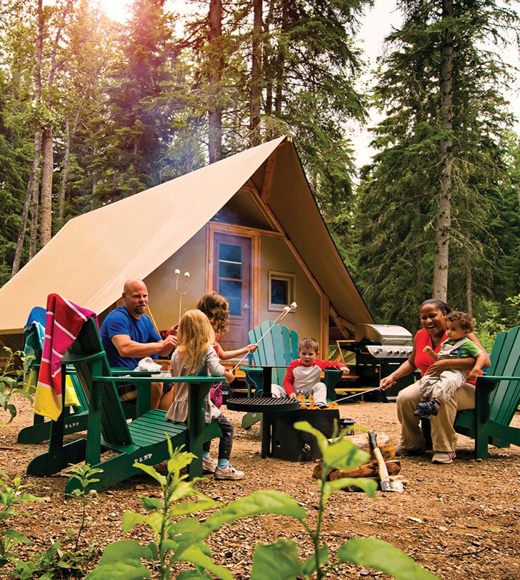 a group of people sitting around a campfire outside of a tent