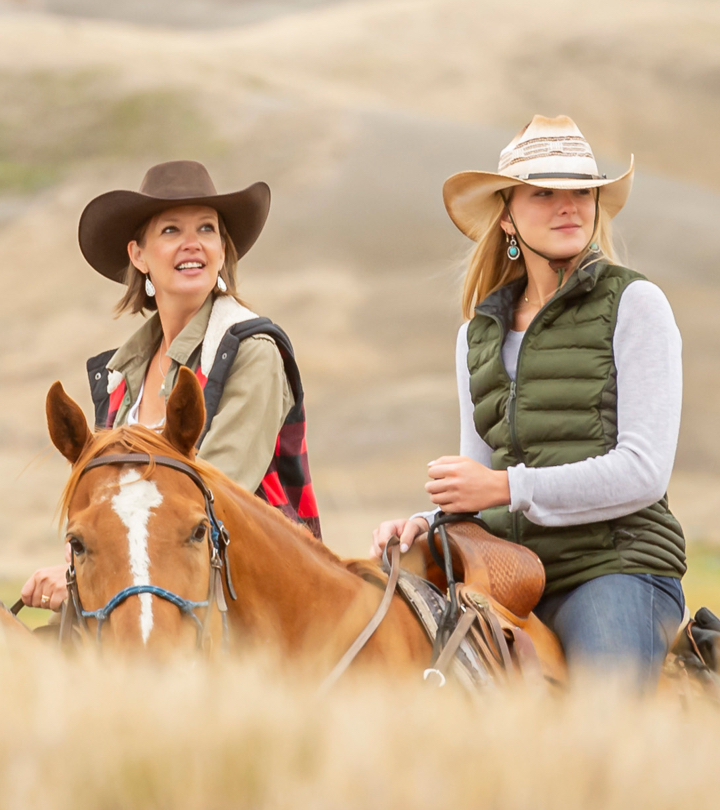 Two women with cowboy hats horseback riding